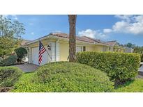 Charming home exterior with a red tile roof, American flag, and well-maintained landscaping at 5566 Avellino Pl, Sarasota, FL 34238