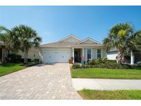 Beautiful single-story home with paver driveway, two-car garage, and lush tropical landscaping at 8077 Sandstar Way, Sarasota, FL 34240