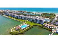 Beautiful aerial view of the condo building, pool, and Intracoastal waterway with beach access in the distance at 8897 Midnight Pass Rd # 407, Sarasota, FL 34242
