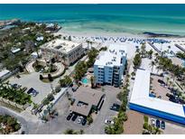 Stunning aerial view of beachfront property with white sand beach and beautiful clear, blue water at 1001 Point Of Rocks Rd # 207, Sarasota, FL 34242