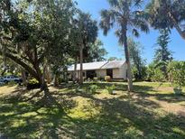 Charming single story house with a metal roof surrounded by mature trees and tropical landscaping at 12127 Hunter Ave, Port Charlotte, FL 33953