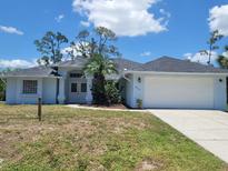 Charming single-story home featuring a two-car garage, manicured lawn, and a welcoming entrance at 1422 Jakway Rd, North Port, FL 34288