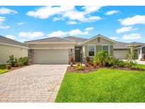 Charming one-story home showcasing a landscaped front yard and brick driveway under a bright, partly cloudy, blue sky at 18317 Gulf Ranch Pl, Bradenton, FL 34211
