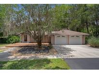 Charming ranch-style home with mature trees, a two-car garage, and a cozy front deck at 22063 Lake Lindsey Rd, Brooksville, FL 34601