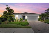 Charming single-story home with a well-manicured lawn, brick driveway, and a two-car garage at 26000 Seastone Dr, Englewood, FL 34223