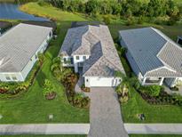 Aerial view of beautiful home with manicured lawn, brick paver driveway, and screened-in lanai, surrounded by lush landscaping at 2794 Butterfly Jasmine Trl, Sarasota, FL 34240