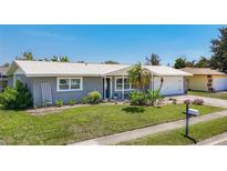 Charming single-story home with a well-manicured lawn, mature landscaping, and a two-car garage, set against a clear blue sky at 2801 21St W Ave, Bradenton, FL 34205