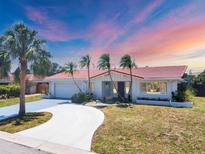 Beautiful single-story home with a red tile roof, lush landscaping, and a private drive at 3426 Brookline Dr, Sarasota, FL 34239