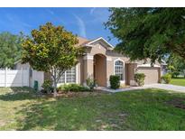Charming single-story home with a well-manicured lawn, mature trees, and a welcoming entryway at 4951 Brightstone Pl, Spring Hill, FL 34609