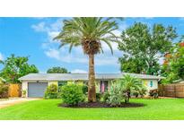 Charming single-story home with a well-manicured lawn, a palm tree, and a gray garage at 5603 1St Avenue Dr Nw, Bradenton, FL 34209