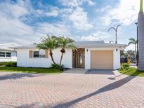 Charming single-story home with a tan garage door, palm trees, and brick paver driveway at 6300 Midnight Pass Rd # 5, Sarasota, FL 34242