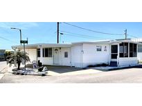 Charming manufactured home with bright white siding, carport, and a cozy screened-in porch in a lovely neighborhood at 72 4Th Ave # 72, Venice, FL 34285
