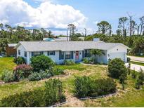 Charming single-story home with lush landscaping, manicured lawn, and a delightful light pink front door at 7690 Castleberry Ter, Englewood, FL 34224