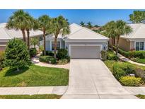 Charming home with a well-manicured front yard, complemented by lush landscaping and swaying palm trees at 8731 52Nd E Dr, Bradenton, FL 34211