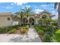 Charming home featuring a tiled roof, black front door, and lush landscaping with palm trees and colorful flowers at 9635 Discovery Ter, Bradenton, FL 34212