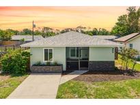 Charming home with manicured lawn, gray roof and accents, complemented by flowering bushes at 1040 Hope St, Venice, FL 34285
