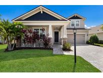 Charming two-story home featuring a beautifully landscaped front yard and a welcoming covered porch with stone accents at 11411 Spring Gate Trl, Bradenton, FL 34211