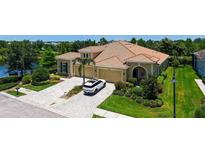 Stunning home featuring a tile roof, three-car garage, lush landscaping, and a brick driveway by a beautiful pond at 11603 Bluebird Pl, Lakewood Ranch, FL 34211