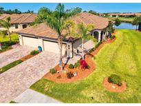 Stunning home featuring lush landscaping, brick driveway, and a three-car garage at 12230 Amica Loop, Venice, FL 34293