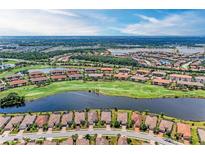 Stunning aerial view of a golf course community, featuring homes, lakes, and lush green fairways under a sunny sky at 13711 Messina Loop # 102, Lakewood Ranch, FL 34211