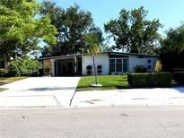 Charming single-story home with a well-manicured lawn and modern design, featuring mature trees and a spacious driveway at 1801 Marilyn Ave, Bradenton, FL 34207