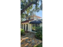 Charming home exterior with arched entryway, black awning, and well-kept landscaping at 219 24Th W St, Bradenton, FL 34205