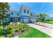 Beautiful blue townhome with a two-car garage and lush landscaping in the front yard at 305 Via Tuscany Ave, Sarasota, FL 34243