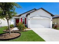 Charming one-story home with a well-manicured lawn, colorful flowers, and a bright red front door at 4739 Reisswood Loop, Palmetto, FL 34221