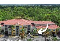 Condo building featuring colorful siding, a red tile roof, and lush landscaping at 5401 Bentgrass Dr # 1-113, Sarasota, FL 34235