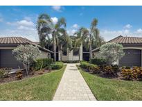 Beautiful condo exterior featuring lush landscaping, garages, and a welcoming walkway at 5624 Palmer Cir # 206, Bradenton, FL 34211