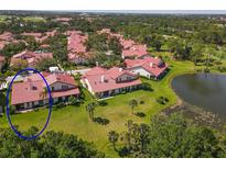 An aerial view of a villa community featuring a pond and lush landscaping; each villa has a terracotta-tile roof at 7331 Villa D Este Dr, Sarasota, FL 34238