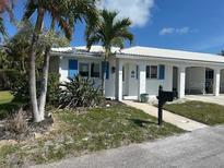 Charming single-story home with a white tile roof, blue shutters, and tropical landscaping at 754 Spanish S Dr # 754, Longboat Key, FL 34228