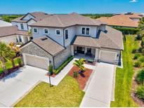 Stunning two-story home with a stone-accented facade, lush landscaping, and a spacious three-car garage at 8272 Summer Night Rd, Sarasota, FL 34241