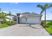 Beautiful home featuring a paved driveway, two-car garage, and tropical landscaping under a clear blue sky at 10030 Degas Ter, Bradenton, FL 34212