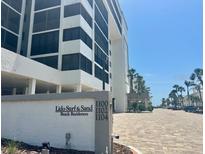 Beautiful exterior view of Lido Surf & Sand Beach Residences condo building with well-manicured landscaping at 1100 Benjamin Franklin Dr # 802, Sarasota, FL 34236