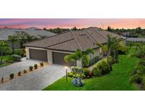 Beautifully landscaped exterior of home with three-car garage and brick driveway at sunset at 16012 Sunny Day Dr, Bradenton, FL 34211