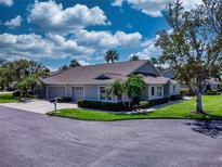 Well-maintained exterior of home with green grass, palm trees, landscaping, driveway, and two-car garage at 1612 Fairway Oaks Dr, Palmetto, FL 34221