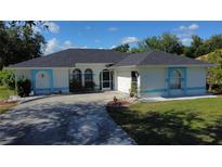 Charming single-story home with blue trim, landscaped front yard, and inviting curved driveway at 21498 Beaverton Ave, Port Charlotte, FL 33952