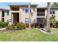 Beautiful condo exterior featuring lush landscaping with green grass, plants, and palm trees at 4061 Crockers Lake Blvd # 27, Sarasota, FL 34238