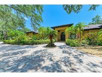 Stunning home featuring lush landscaping, mature trees, and a circular paver driveway at 4647 Stone Ridge Trl, Sarasota, FL 34232