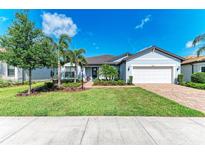 Beautiful single-story home featuring a well-manicured lawn, mature trees, and a two-car garage at 7136 Summerland Cv, Bradenton, FL 34202