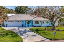 Charming light blue home with a well manicured lawn, curved driveway and welcoming front porch with blue seating at 7817 Alhambra Dr, Bradenton, FL 34209
