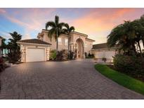 Stately home with lush landscaping, paver driveway, and porte cochere garages at sunset at 801 3Rd E St, Palmetto, FL 34221