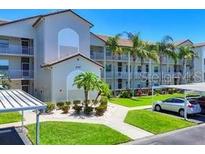 Exterior view of building featuring well-maintained landscaping and covered parking on a bright, sunny day at 8755 Olde Hickory Ave # 7107, Sarasota, FL 34238
