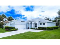 Charming single-story home with manicured lawn and lush landscaping creating excellent curb appeal at 8979 Grey Oaks Ave, Sarasota, FL 34238