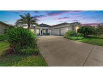Beautiful home exterior with well-manicured landscaping, long driveway, and attached two-car garage at dusk at 1219 Thornbury Dr, Parrish, FL 34219