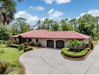 Stunning home showcasing lush landscaping, a circular driveway, and a terracotta-tiled roof at 1401 Pelican Ln, North Port, FL 34286