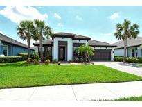 Beautiful single-story home with tropical landscaping, well-manicured lawn, and a two-car garage at 1919 Woodleaf Hammock Ct, Bradenton, FL 34211