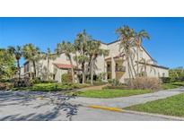 A beautiful home exterior featuring lush landscaping, mature palm trees, and unique architectural details at 2055 Gulf Of Mexico Dr # G2-108, Longboat Key, FL 34228