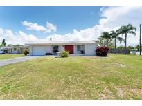Single-story home featuring a bright red front door and well-manicured front yard with mature trees at 4535 Maceachen Blvd, Sarasota, FL 34233
